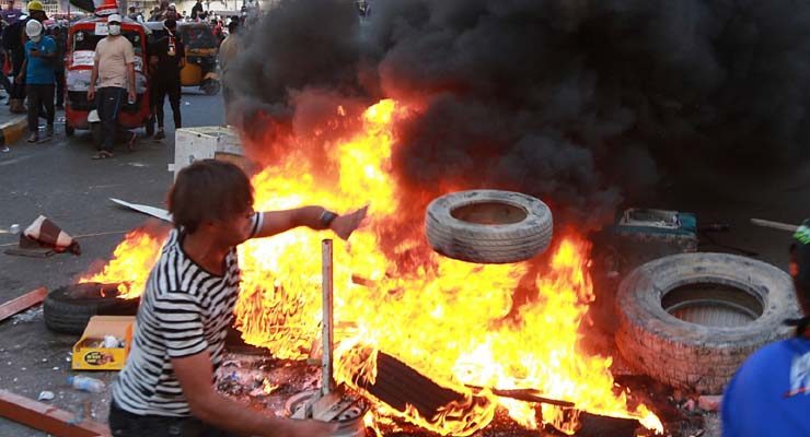 Manifestantes fazem barricada perto de emissora estatal do Iraque em Bagdá nesta segunda-feira (4) — Foto: Khalid Mohammed/AP Photo.