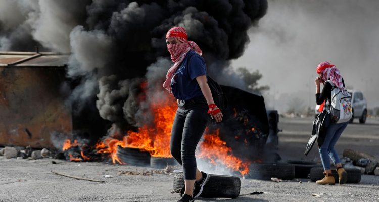 Manifestante palestina é vista na frente de pneus queimados durante protesto anti-Israel perto do assentamento de Beit El na Cisjordânia ocupada por Israel neste sábado (16) — Foto: Mohamad Torokman/Reuters.